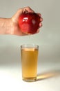 A woman& x27;s hand squeezes fresh juice. Pure apple juice pouring out from fruit into glass. Royalty Free Stock Photo