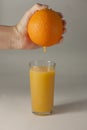 A woman& x27;s hand squeezes fresh juice. Pure orange juice pouring out from fruit into glass. Royalty Free Stock Photo