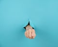 A woman& x27;s hand sticking out of a hole from a blue background shows a fist. Royalty Free Stock Photo