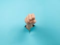 A woman& x27;s hand sticking out of a hole from a blue background shows a fist. Royalty Free Stock Photo