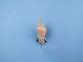 A woman& x27;s hand sticking out of a hole from a blue background shows her index finger up. Royalty Free Stock Photo