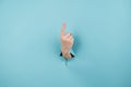 A woman& x27;s hand sticking out of a hole from a blue background shows her index finger up. Royalty Free Stock Photo