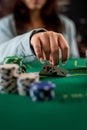 woman's hand takes poker chips and cards from a pile at a round poker table. risky bets in poker Royalty Free Stock Photo