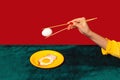 Woman& x27;s hand tasting fried eggs with chopsticks on green and red background. Vintage, retro style interior