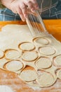 A woman's hand uses a glass to make circles from cookie dough