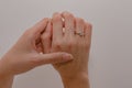 Woman's hands displaying a sparkling diamond engagement ring on a white background.