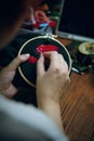 Girl is embroidering mushroom cap on green cloth.