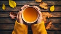 A woman& x27;s hands hold a mug of hot tea in autumn on a wooden table with yellow fallen leaves. A warm and cozy Royalty Free Stock Photo