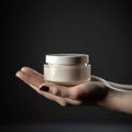 Woman& x27;s hands holding cream jar on gray studio background