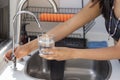 Woman& x27;s hands holding a glass that fills with water from the tap filter