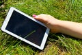 Woman's hands holding tablet laying on grass