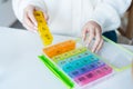 Woman's hands holding daily and weekly pills organizer on the table. Taking daily medicine antioxidant diet vitamin