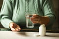 Woman& x27;s hands holds two capsules and glass of water over the table, ready to take medicines. Health care concept. Royalty Free Stock Photo