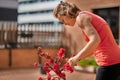 woman in red pruning red flower tree in the balcony Royalty Free Stock Photo