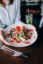 Woman& x27;s hands with salad on table in restaurant