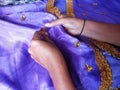 A Woman& x27;s Hands Sewing and Stitching Gold Sequins Onto A Purple Traditional Indonesian Dress