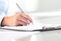 Woman's hands writing on sheet of paper in a clipboard and a pen Royalty Free Stock Photo