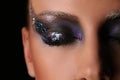 Woman's smokey eye with colorful crystals. Close up. Black background