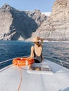 Woman on the yacht nose near the rocky coast