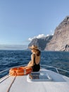 Woman on the yacht nose near the rocky coast