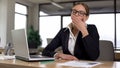 Woman yawning while working on laptop, tired of monotonous work in office Royalty Free Stock Photo