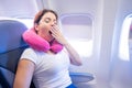 Woman yawns while sitting on the plane by the window.