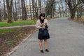 Woman, 45-year-old European woman with long dark hair stands in the park on the alley and looks at a mobile phone Royalty Free Stock Photo