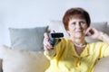 Woman in yellow blouse with TV remote in hand Royalty Free Stock Photo