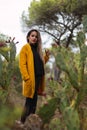 Woman in a yellow coat and hat in hand. Casual fashion