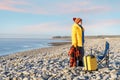 Woman walking and relaxing with yellow suitcase on the seaside at sunrise. British cold winter. Royalty Free Stock Photo