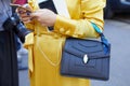 Woman with yellow dress and Bulgari Serpenti bag looking at smartphone before Luisa Beccaria