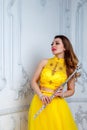 Woman in yellow dress with flute on light textured background