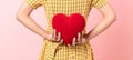 Woman in a yellow dress holding red hearts on pink background. Royalty Free Stock Photo