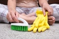 Woman in yellow gloves with a green brush is so tired of cleaning and brushing carpet, removing stains and wool from it and doing Royalty Free Stock Photo