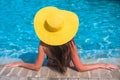 Woman in yellow hat relaxing at swimming pool