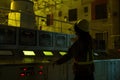 A woman in a yellow helmet is standing in front of a control panel Royalty Free Stock Photo