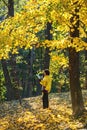 Woman in yellow jacket reads in autumn forest