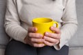 Woman with a yellow mug, commonly enjoyed for tea and coffee