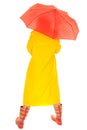 Woman in yellow rain coat under red umbrella back