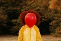 Woman in a yellow raincoat holding a red balloon on the background of forest. Royalty Free Stock Photo