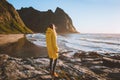 Woman in yellow raincoat walking alone on Kvalvika beach in Norway