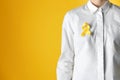 Woman with yellow ribbon against color background. Cancer awareness concept Royalty Free Stock Photo