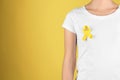 Woman with yellow ribbon on color background. Cancer awareness concept Royalty Free Stock Photo