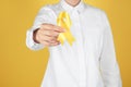 Woman with yellow ribbon on color background. Cancer awareness concept Royalty Free Stock Photo