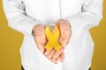 Woman with yellow ribbon on color background, closeup. Cancer awareness concept Royalty Free Stock Photo