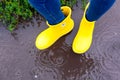Woman in yellow rubber boots standing in the puddle in rain