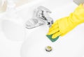 Woman in yellow rubber gloves is cleaning bathroom sink with detergent Royalty Free Stock Photo