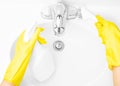 Woman in yellow rubber gloves is cleaning bathroom sink with detergent Royalty Free Stock Photo