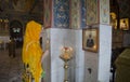 A woman in yellow scarf offering prayer to a saint in a church with Orthodox belief and tradition
