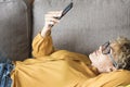 Woman with yellow shirt enjoy time and leisure at home laying on the sofa and using mobile phone connection, People and technology